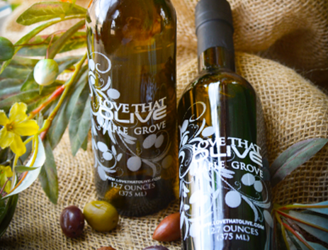 Image of olive oil bottles on burlap sac with olives and leaves